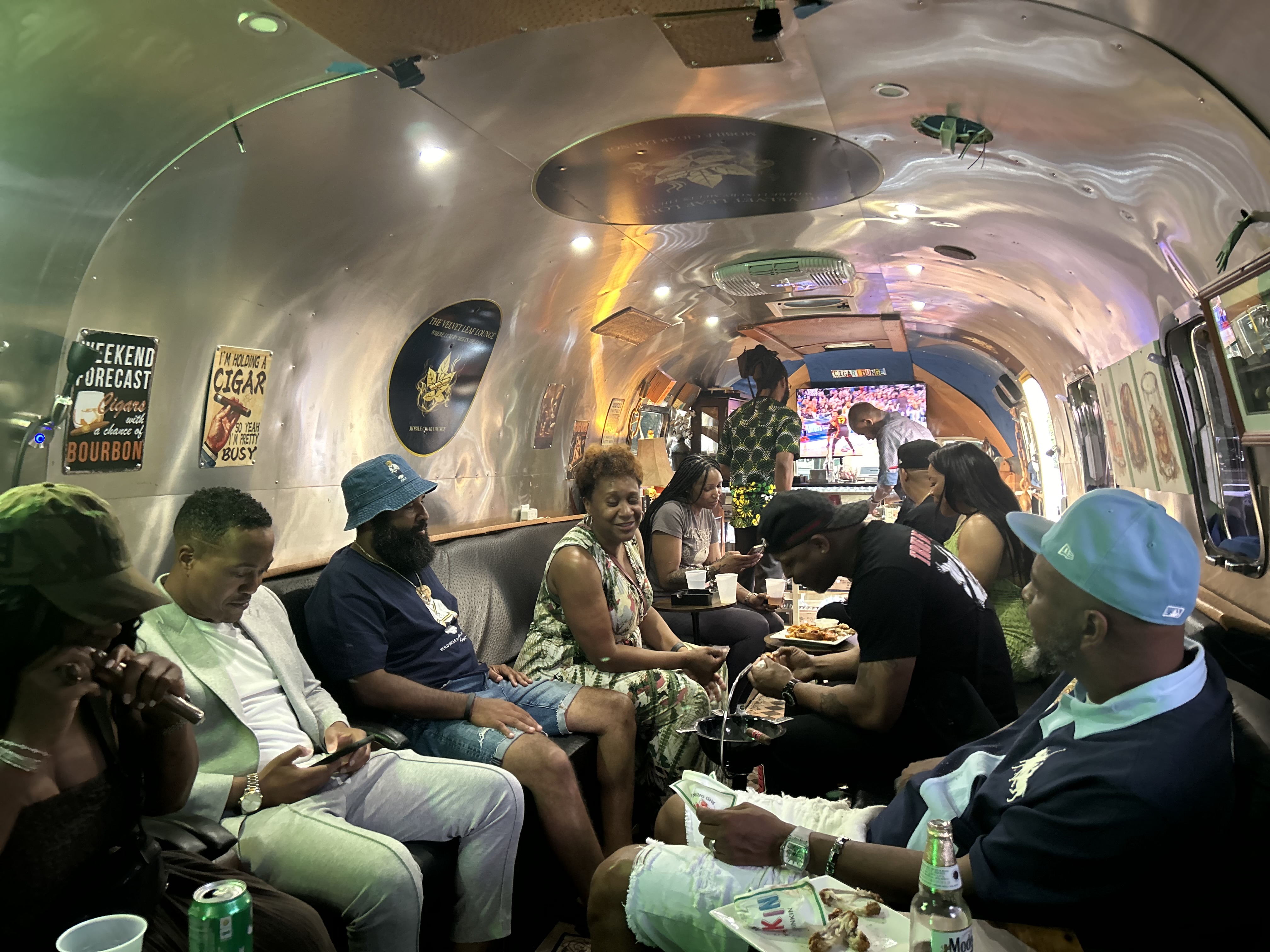 Inside the Airstream lounge — vintage signage, leather bench seating, and guests enjoying the game